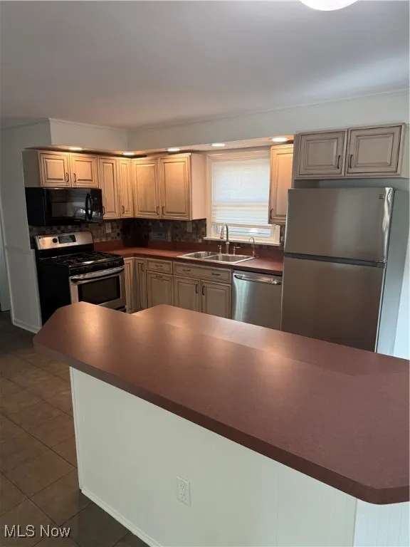 Kitchen with dark countertops, fridge, stove, dishwasher, and decorative backsplash