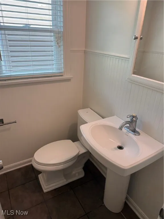 Half bathroom with wainscoting and tile patterned flooring