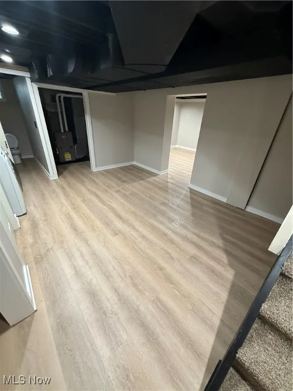 Finished below grade area with light wood-style flooring and baseboards