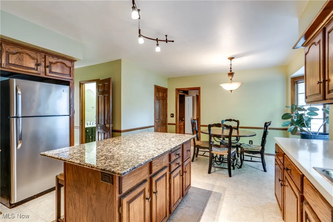 Kitchen featuring freestanding refrigerator, a center island, and brown cabinets