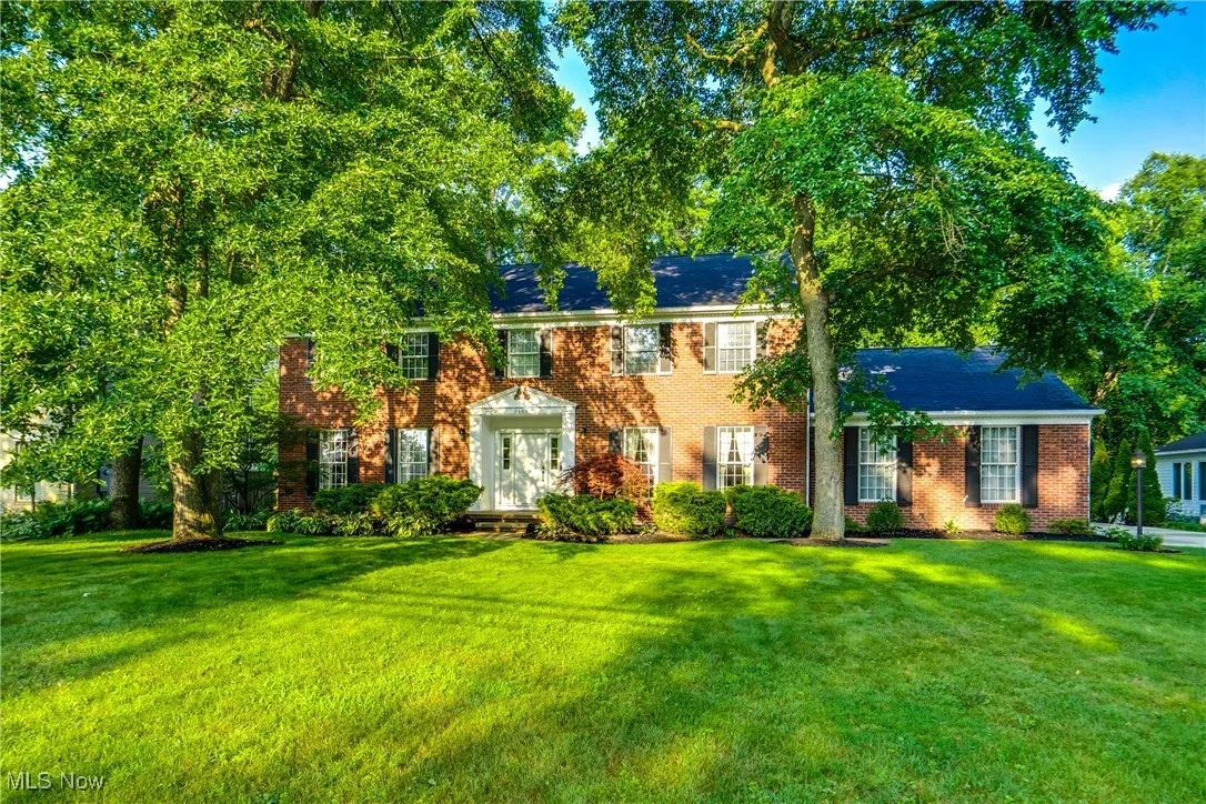 Colonial home featuring brick siding and a front lawn