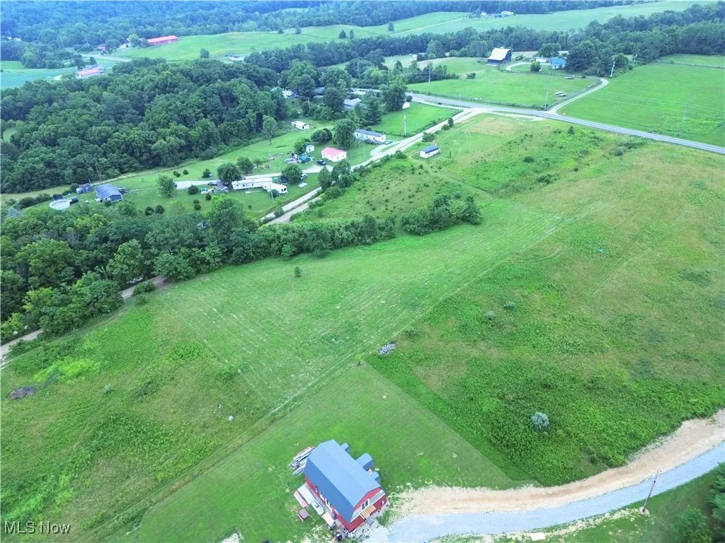 Aerial view of property and surrounding area featuring rural landscape and a tree filled landscape