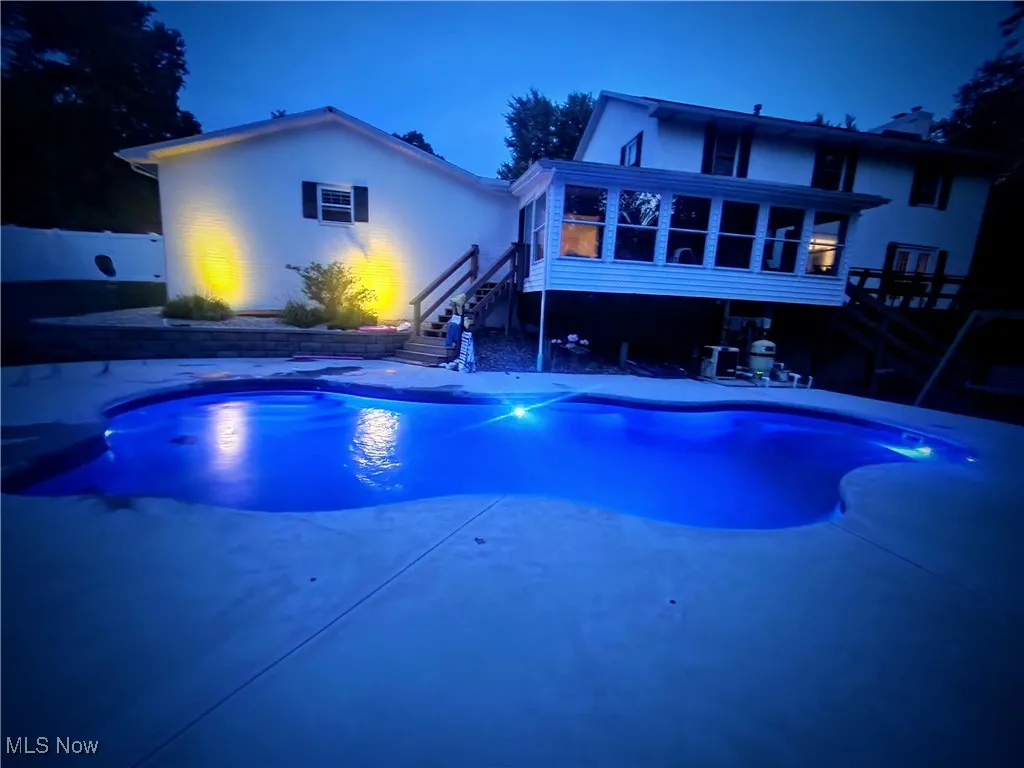 Outdoor pool featuring stairway, a sunroom, and a patio area