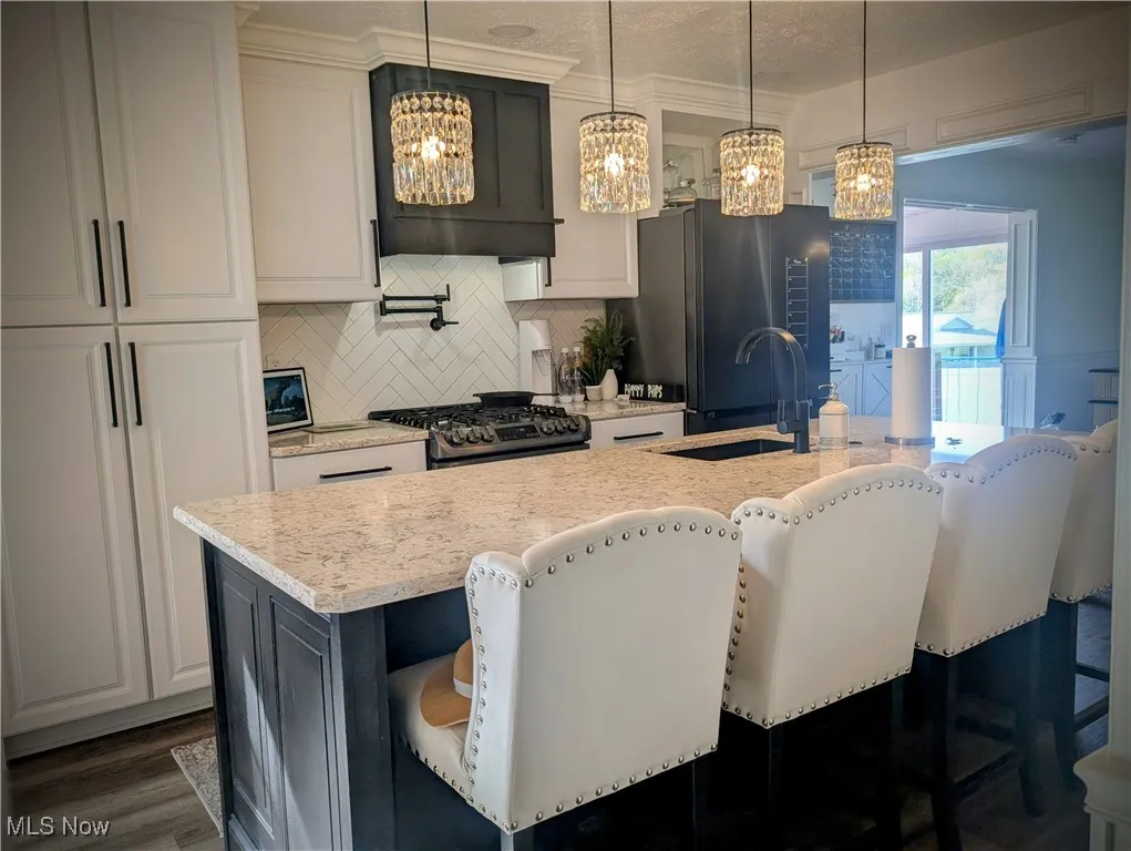 Kitchen featuring a chandelier, stainless steel appliances, tasteful backsplash, and a kitchen island with sink