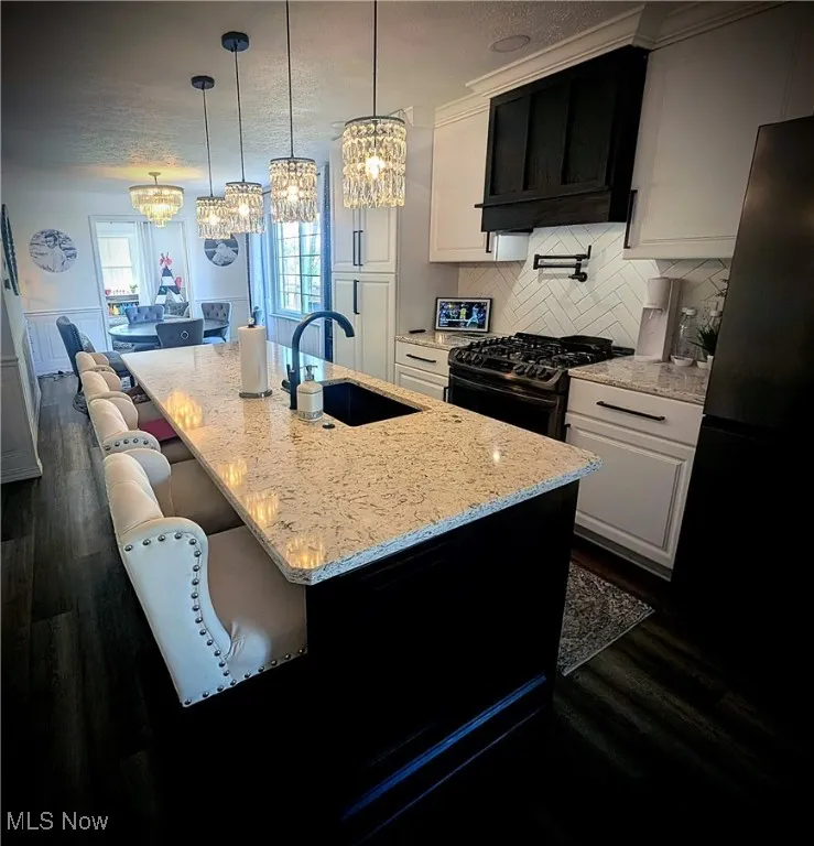 Kitchen featuring a chandelier, dark wood-style flooring, white cabinetry, and gas range