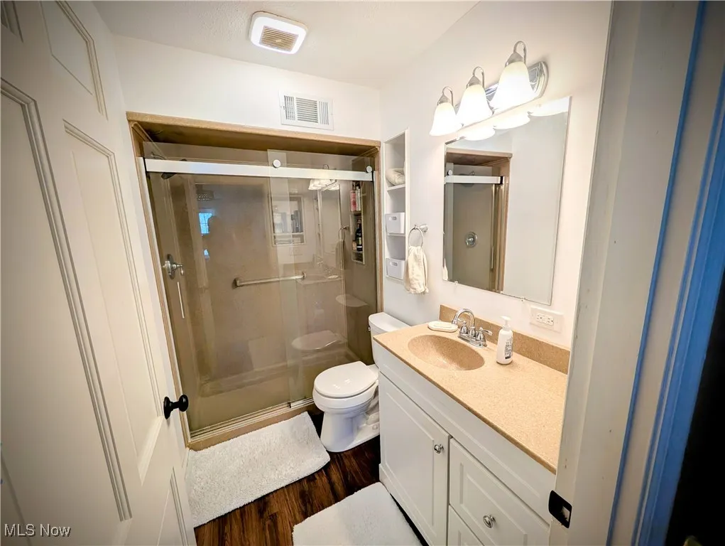 Bathroom featuring a stall shower, vanity, and wood finished floors