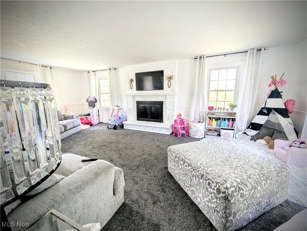 Bedroom with carpet flooring, a brick fireplace, and multiple windows