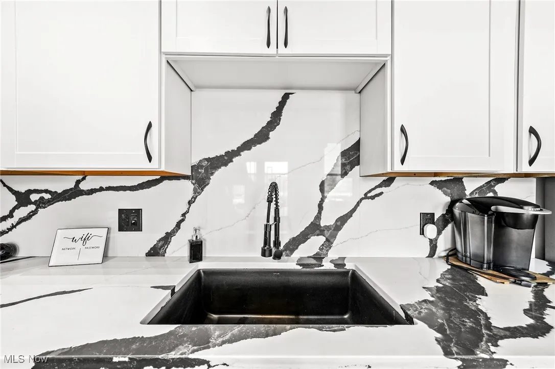 Kitchen view of white cabinets and light stone counters