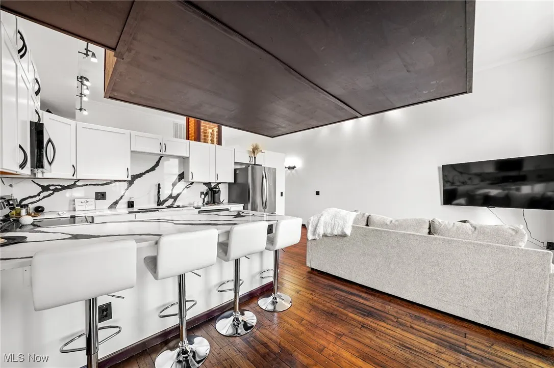 Kitchen with a peninsula, open floor plan, dark wood finished floors, a breakfast bar, and white cabinetry