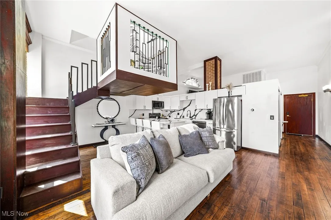 Living area featuring ornamental molding, dark wood-style floors, and stairway