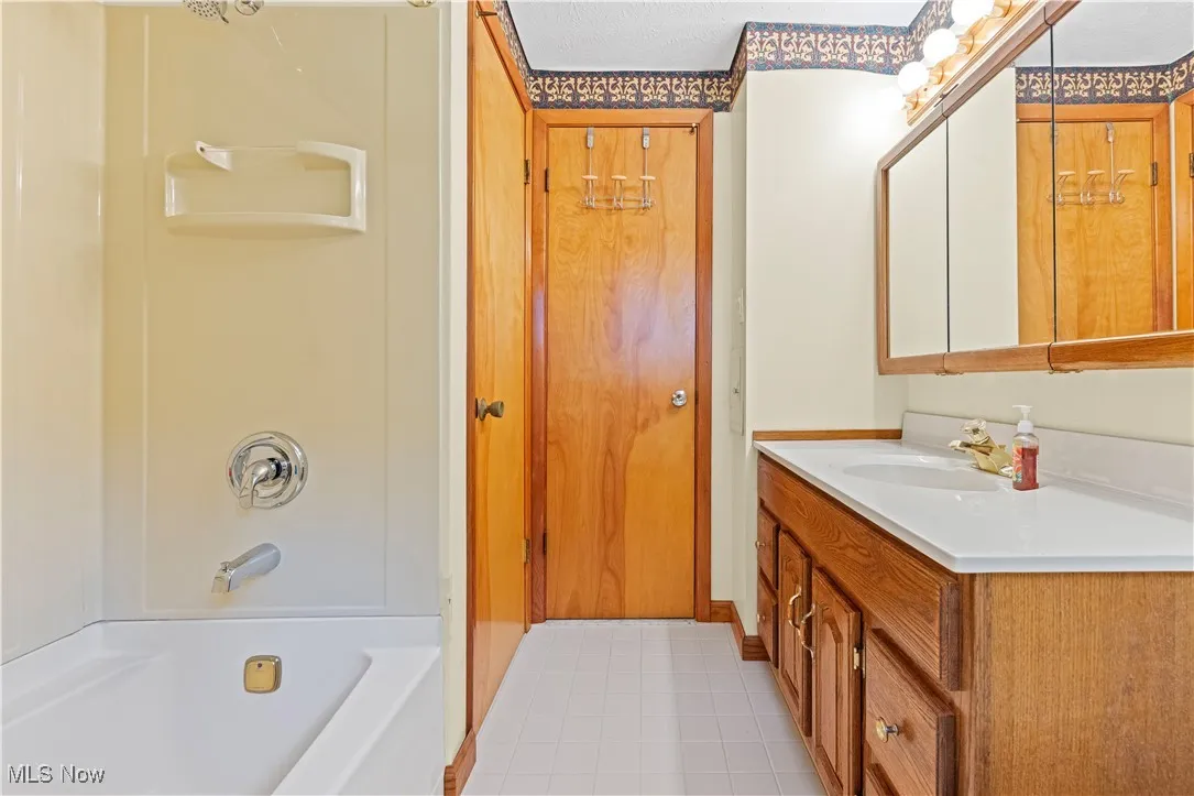Full bath with vanity, tile flooring, and shower / bathtub combination