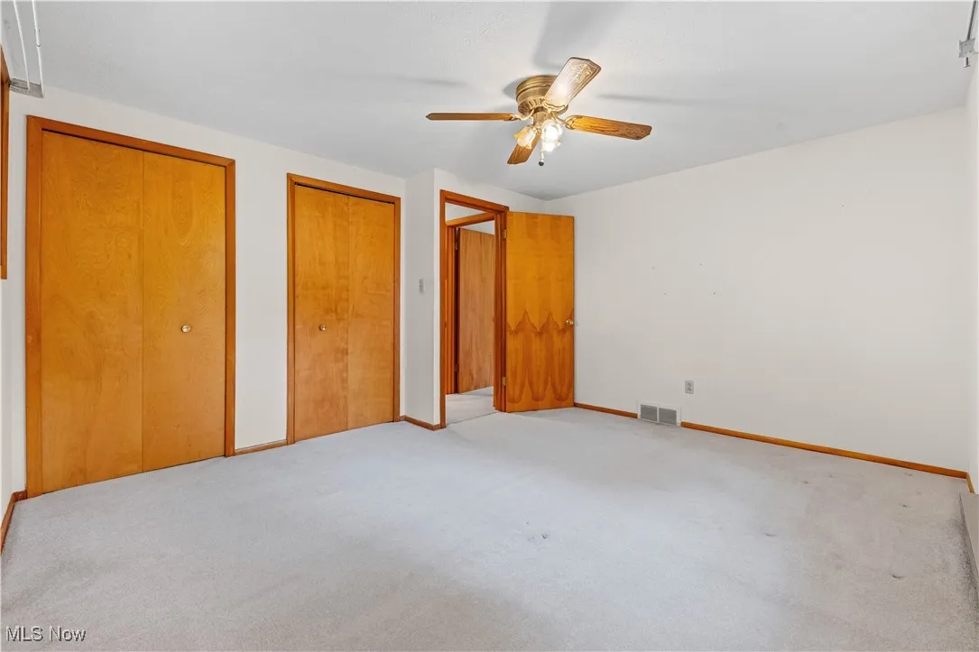 Bedroom featuring light carpet, two closets, and ceiling fan