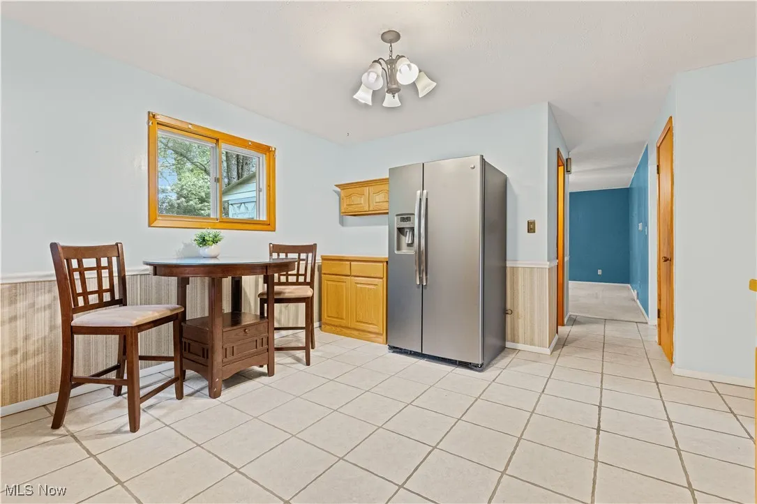 Eat-in kitchen featuring light tiled floors and stainless fridge.