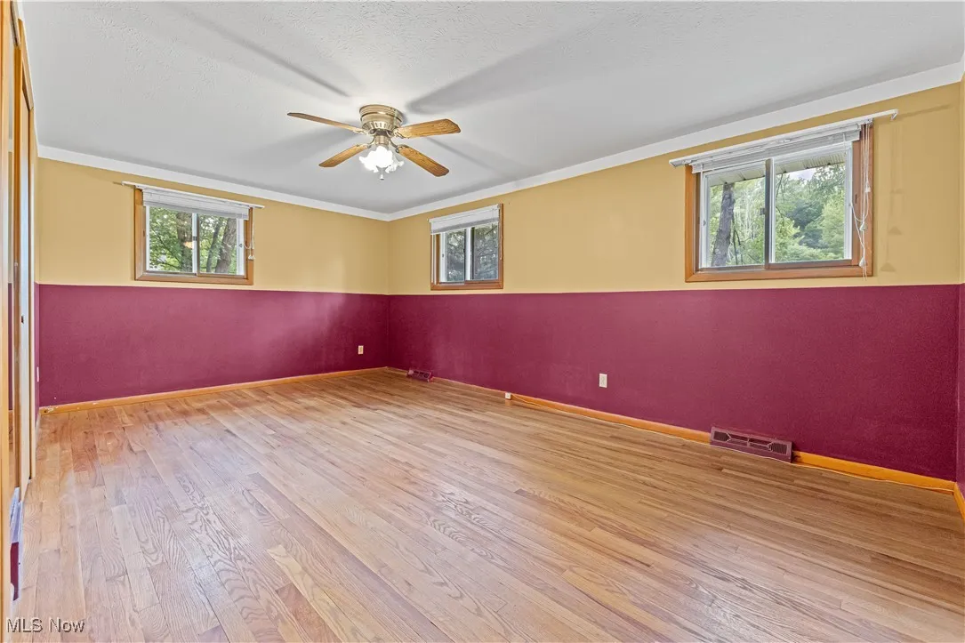Spacious primary room featuring light wood finished floors, ceiling fan, and crown molding