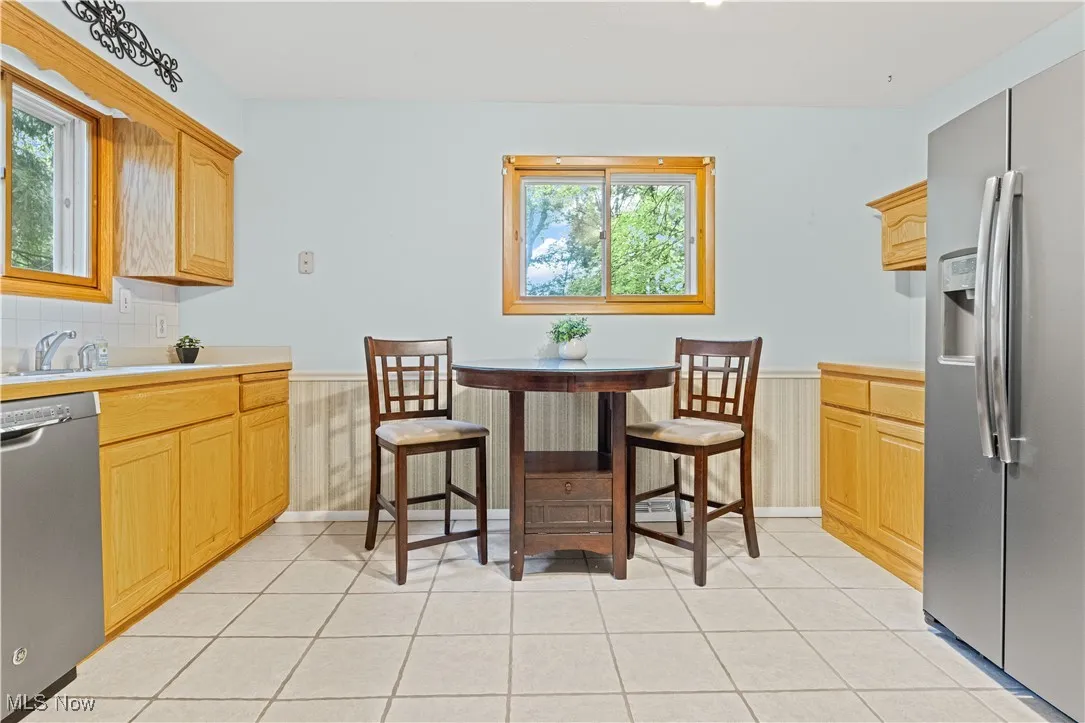 Eat-in kitchen with stainless steel appliances, light countertops, and light tiled floors