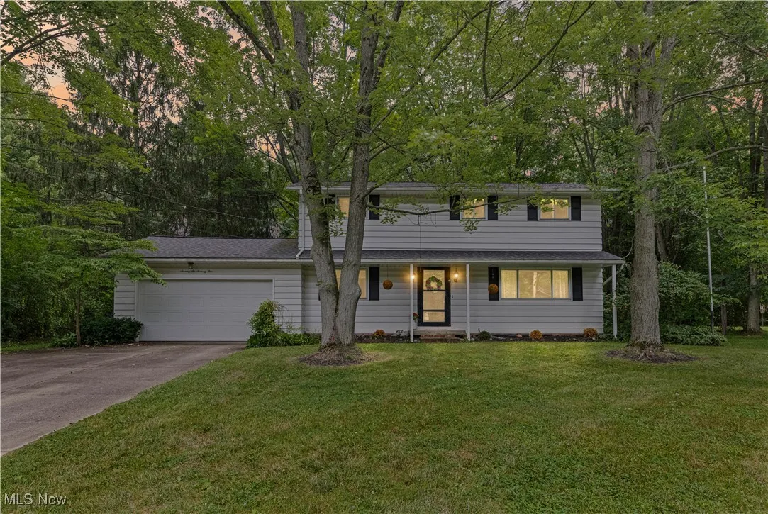 Traditional-style house featuring an attached garage, driveway, and a front lawn