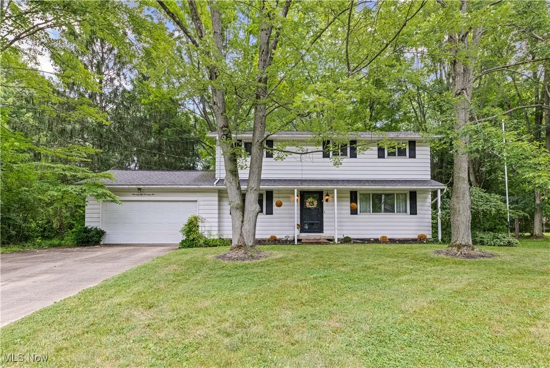 Colonial-style home with an attached garage, driveway, and a front lawn