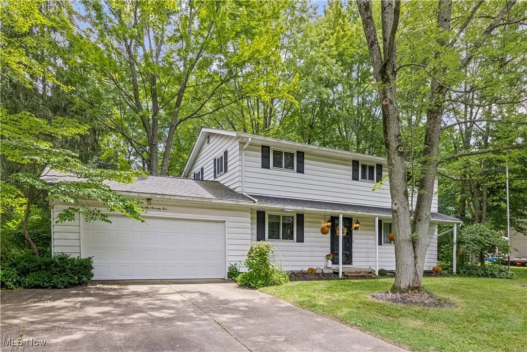 Colonial home with concrete driveway, a garage, and a front lawn