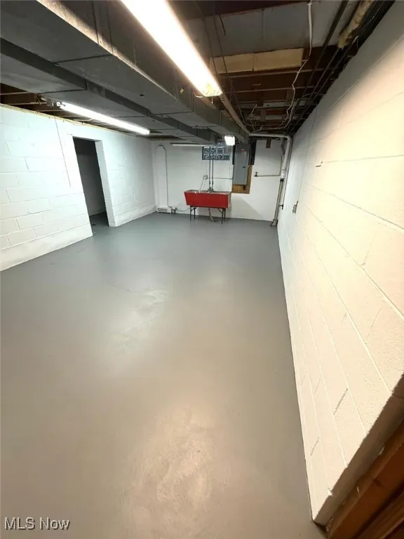 Basement with electric panel and concrete block wall