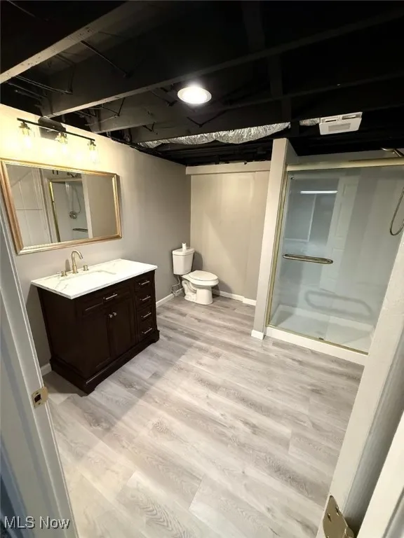 Bathroom with a stall shower, vanity, and wood finished floors
