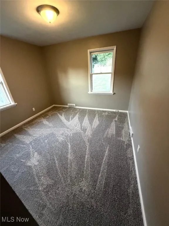 Carpeted empty room featuring baseboards