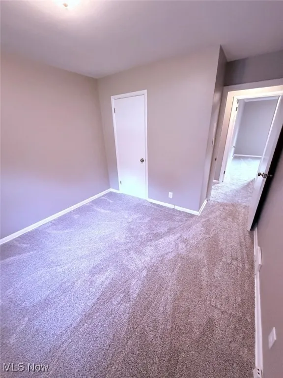 Carpeted empty room with baseboards