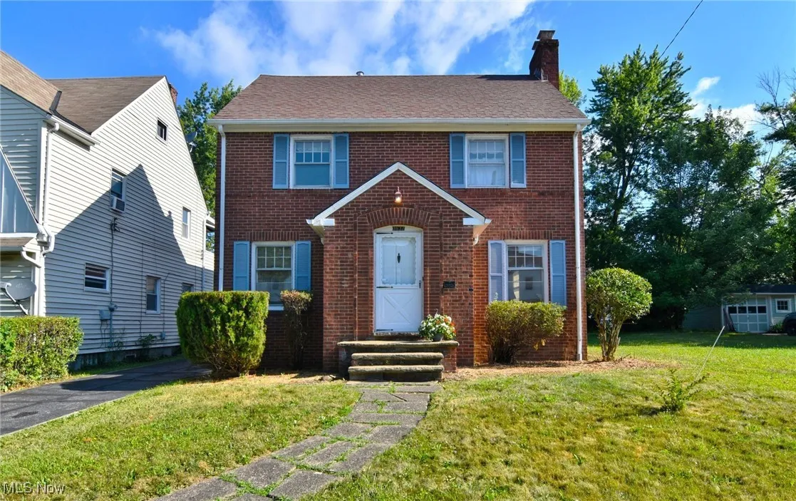 Colonial home featuring brick siding, a front lawn, a chimney, and a shingled roof