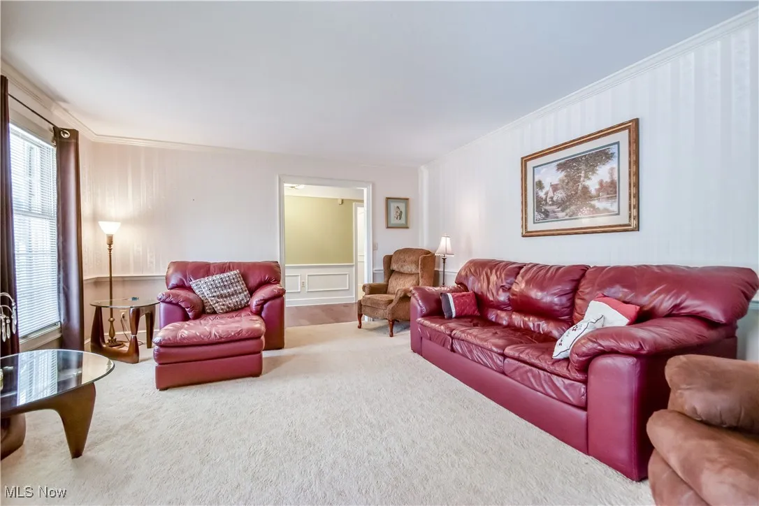 Carpeted living area featuring crown molding and a decorative wall