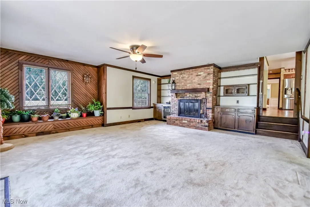  featuring a fireplace, ceiling fan, carpet, crown molding, and wooden walls