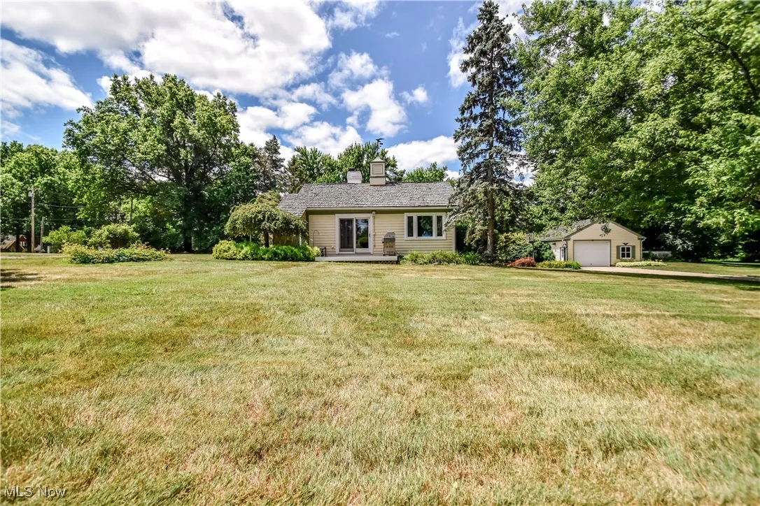 View of front of property featuring a front yard, a detached garage, and a chimney