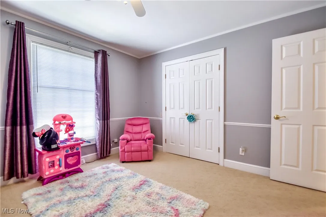 Carpeted bedroom featuring ornamental molding, ceiling fan, and a closet
