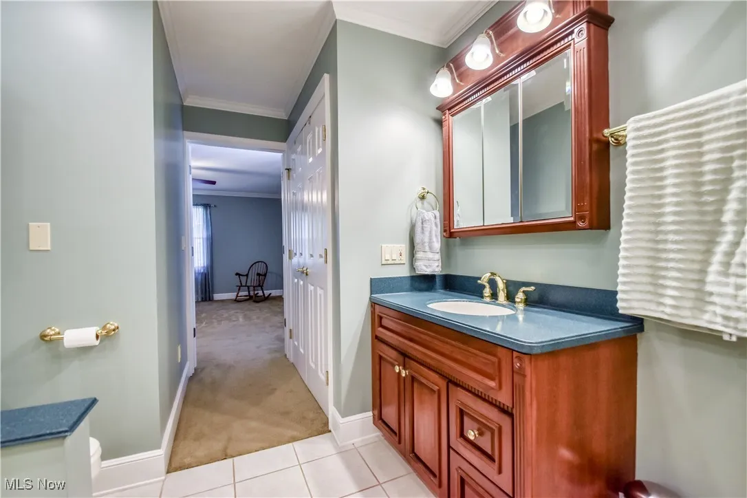 Bathroom with ornamental molding, vanity, and tile patterned floors