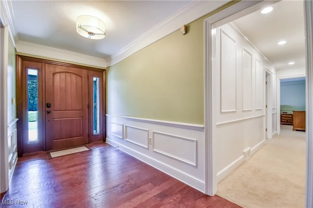 Entrance foyer with ornamental molding, wood finished floors, wainscoting, and recessed lighting