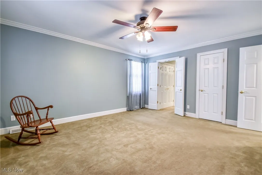 Unfurnished room with crown molding, carpet floors, and a ceiling fan