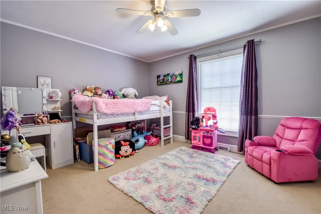 Bedroom with carpet flooring, ceiling fan, and ornamental molding