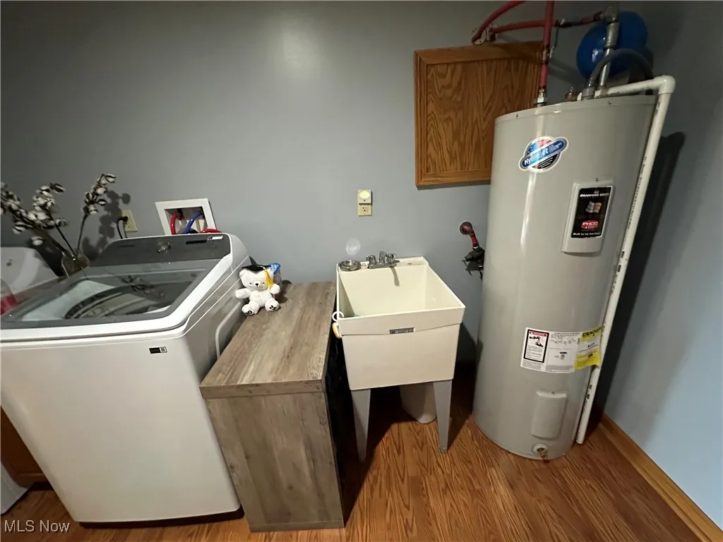Laundry area featuring washer / clothes dryer, water heater, and wood finished floors