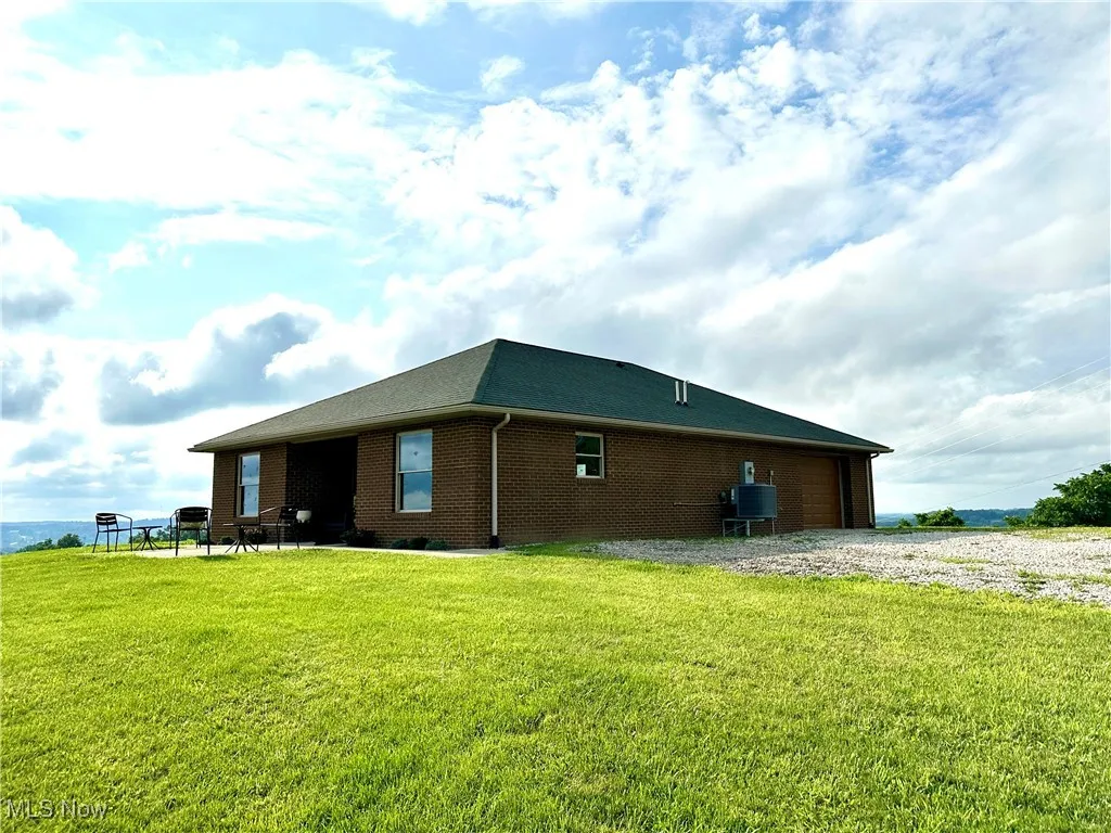 View of home's exterior with brick siding, a yard, and a garage