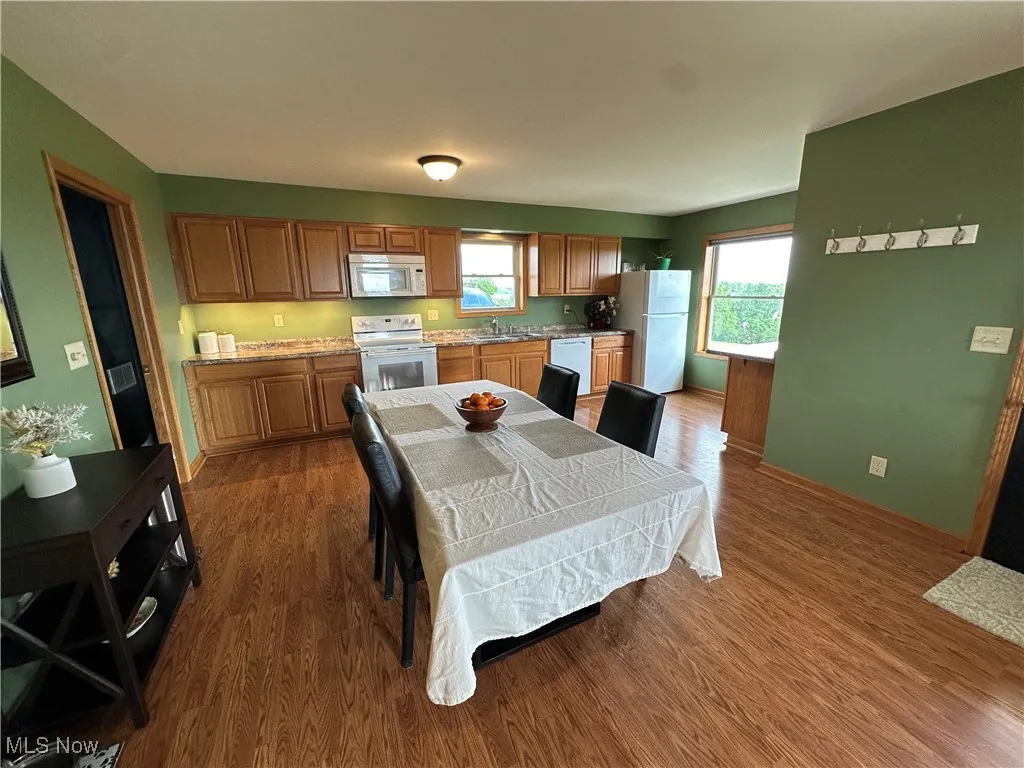 Kitchen featuring white appliances, wood finished floors, and brown cabinetry