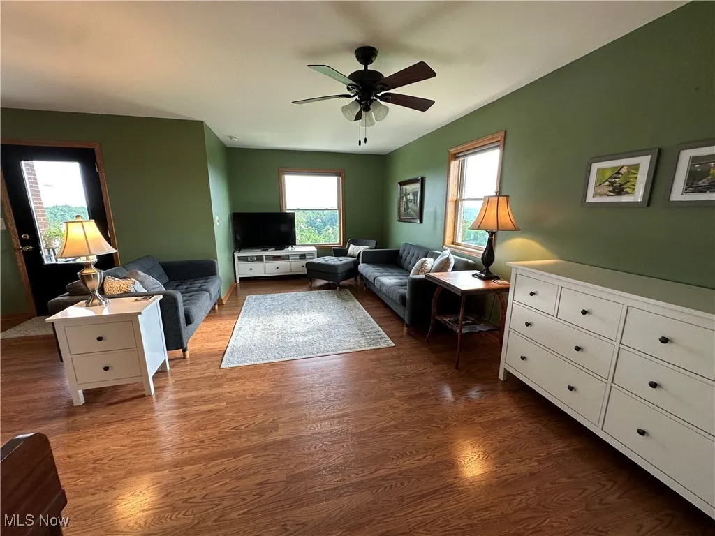 Living area with dark wood-type flooring and ceiling fan