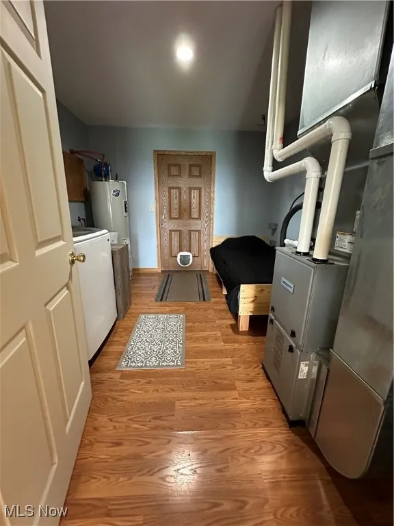 Washroom with washer / dryer, heating unit, light wood finished floors, and water heater