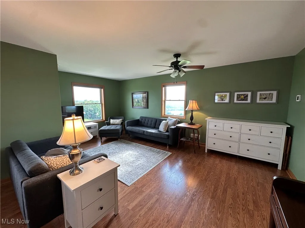 Living area with a ceiling fan and dark wood-style floors
