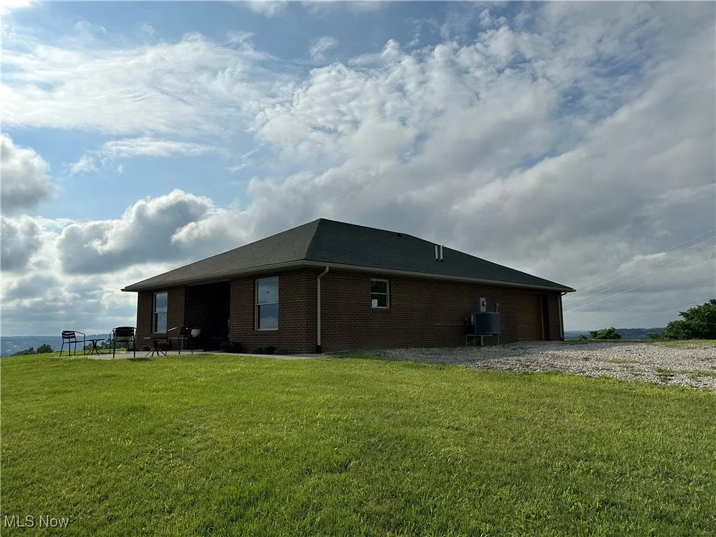 View of property exterior featuring brick siding and a lawn