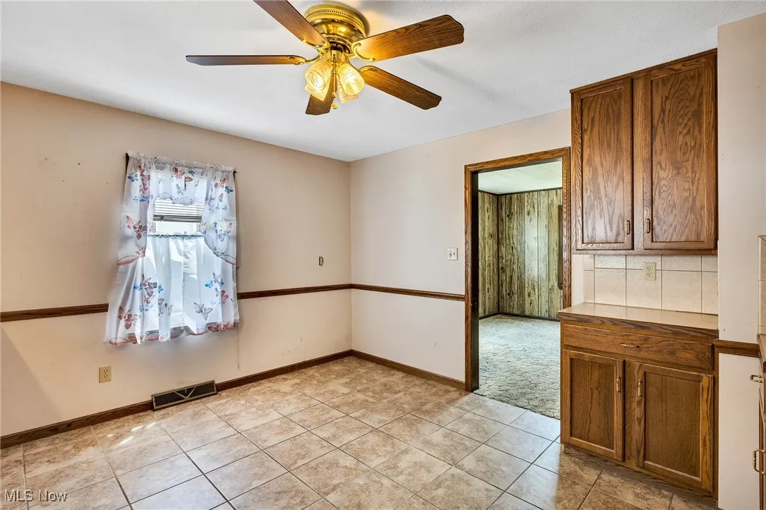 Unfurnished room with light tile patterned floors and ceiling fan