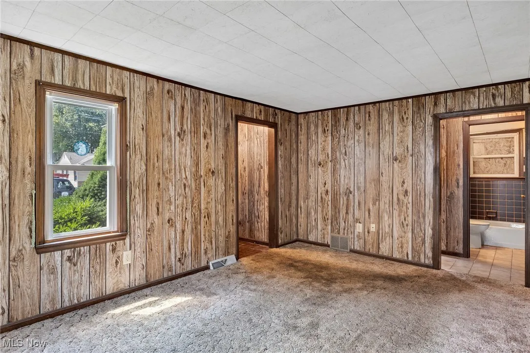 Carpeted empty room with wooden walls and baseboards