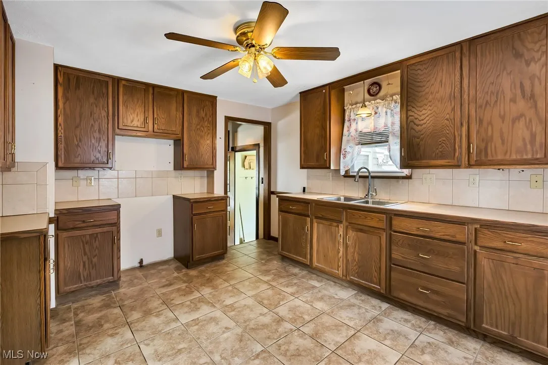 Kitchen with tasteful backsplash, a ceiling fan, and light countertops