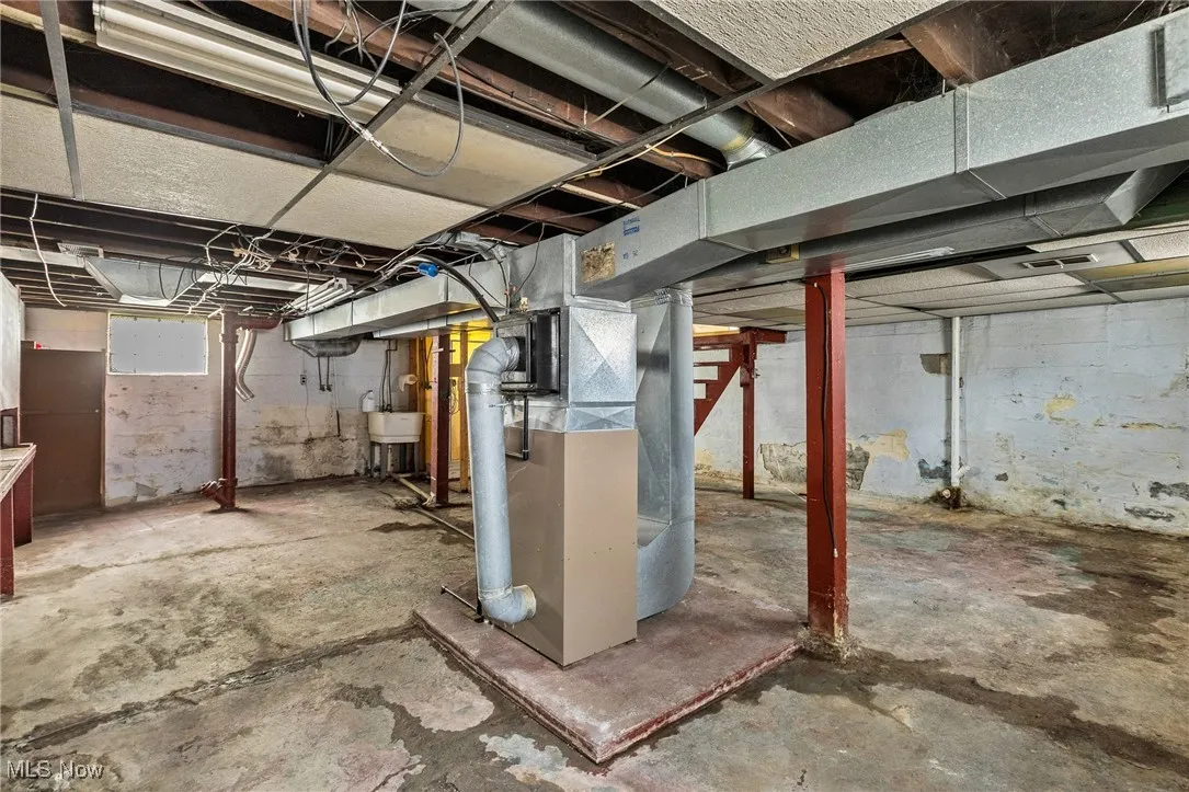 Below grade area featuring heating unit and a sink