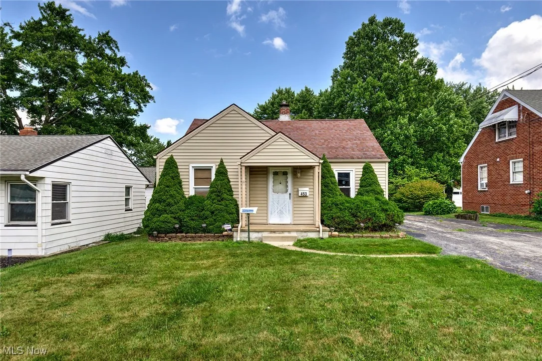Bungalow featuring a front lawn, a chimney, and asphalt driveway