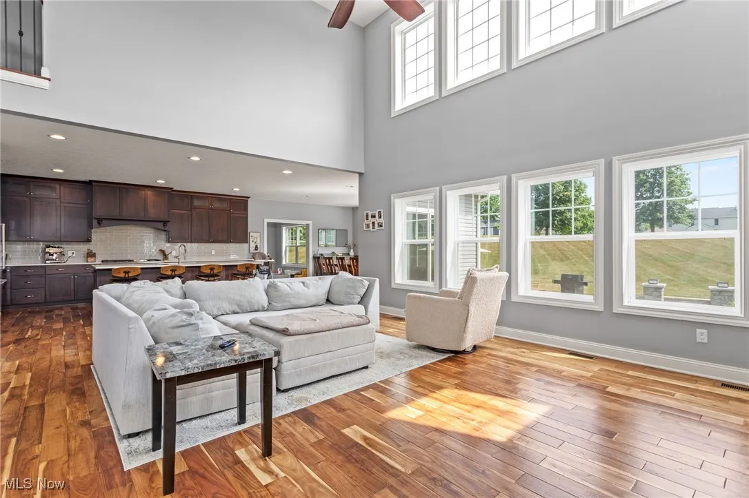 Living room with a ceiling fan, dark wood finished floors, a towering ceiling, and recessed lighting