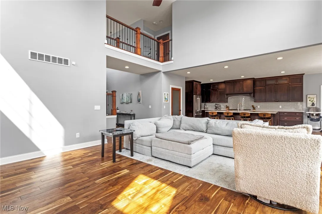 Living area featuring wood finished floors, a towering ceiling, and recessed lighting