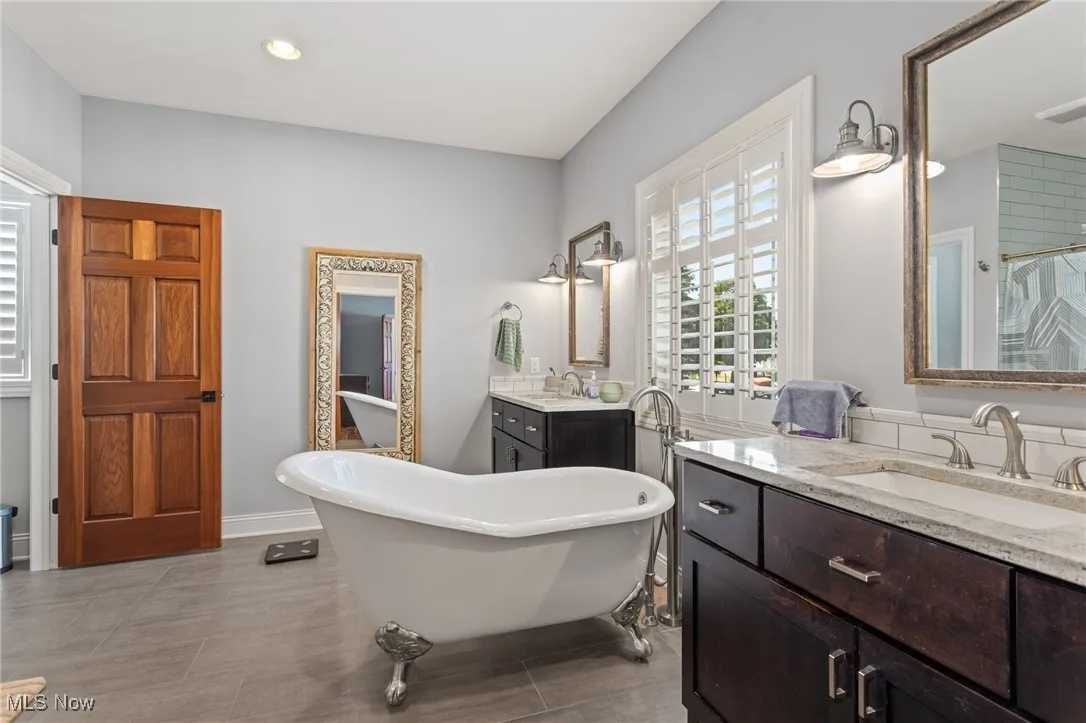 Bathroom with two vanities, a freestanding bath, recessed lighting, and a shower